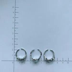 Macro detail of three silver lava rings featuring moonstone and heart zircon on a scale