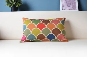 Kissenbezug mit buntem geometrischem Fischschuppenmuster auf einem weißen Sofa