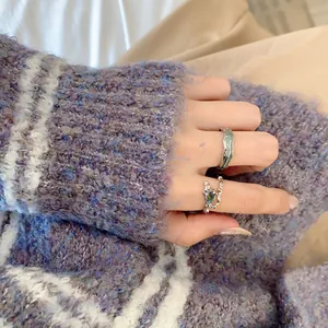 Nahaufnahme einer Hand mit minimalistischen verstellbaren silbernen Ringen in Minzgrün