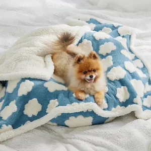 Manta suave de vellón para mascotas con diseño de nubes blancas y un perro pequeño.