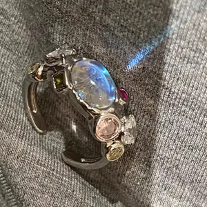 Close-up of a silver molten ring with a glowing moonstone and colored cubic zirconia