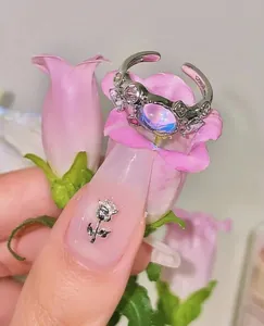 Macro detail of silver open ring with moonstone and pink zircons on a flower