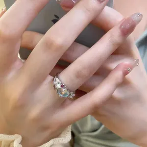 Close-up of lava textured open ring with moonstone and colorful zircons on finger
