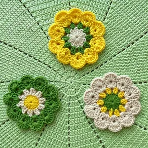 Dettaglio di sottobicchieri a fiore fatti a mano all'uncinetto in filato giallo e verde.