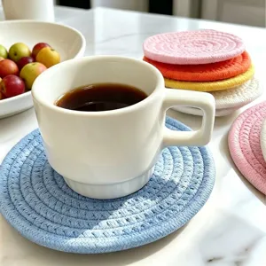 Macro view of a colorful braided cotton rope coaster holding a white coffee cup.