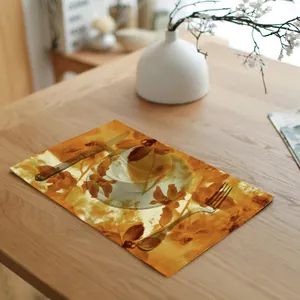Detail van een gele bloemen linnen placemat op een houten eettafel met bestek en servies