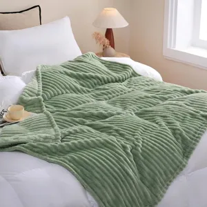 Nahaufnahme einer gemütlichen, grünen Fleece-Heimdecke auf einem modernen weißen Bett