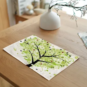 Detailed view of the artistic green tree and ladybug pattern on a white linen placemat