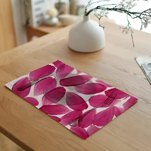 Linnen placemat met levendige roze bloemblaadjes op een moderne houten eettafel.