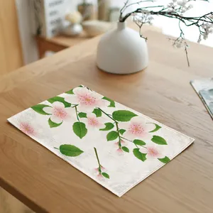 Detailed view of rectangle placemat with pink flower and green leaf pattern on wood table
