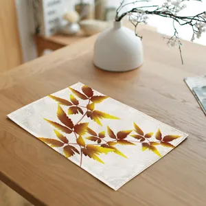 Detail view of rectangular placemat featuring autumn leaf print on wooden table