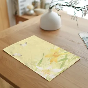 Gele linnen placemat met leliemotief op een houten eettafel