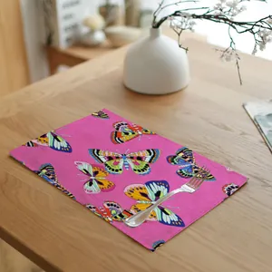 Close-up of pink linen placemat with butterfly print and silver fork on a light wood table.