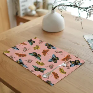 Detail of pink linen placemat with colorful butterfly pattern on wooden table