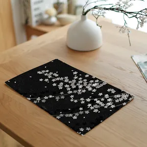 Detailopname van zwart linnen placemat met witte kersenbloesemprint op een houten tafel