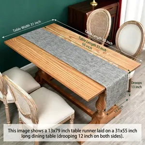 Detail of a grey linen table runner draped over a wooden dining table with size dimensions