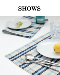Detailed view of blue checkered linen placemats styled with tableware on a white table.
