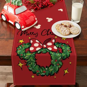 Vista detallada de un camino de mesa navideño rojo con diseño de lazo y corona