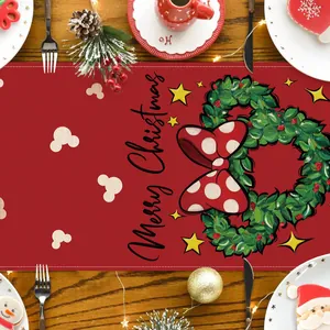 Un camino de mesa navideño rojo festivo con diseño de corona sobre mesa de madera