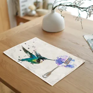 Close-up detail of watercolor hummingbird linen placemat on a wooden dining table