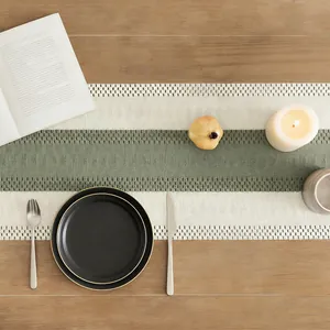 Top view of textured sage green and cream linen table runner on a wooden surface