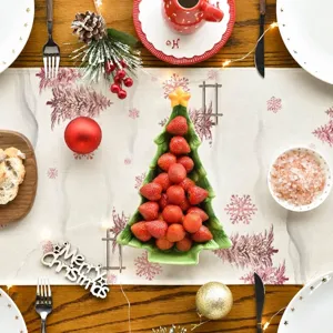 Camino de mesa navideño rosa con estampados de copos de nieve en una mesa festiva