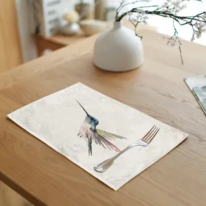 Close-up of linen placemat with watercolor hummingbird print and a silver fork