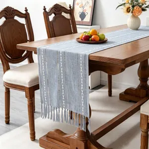 Blue boho table runner with tassels on a wooden dining table