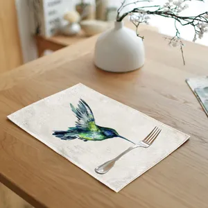 Detailed view of watercolor hummingbird linen placemat on a wooden dining table with fork