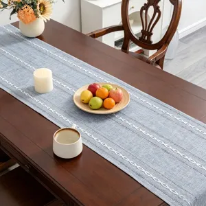 Detail of blue cotton linen table runner with white embroidered stripes and tassels