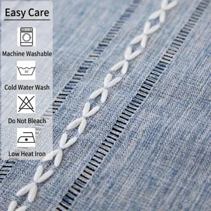 Macro detail of blue cotton linen table runner featuring white embroidery and striped jacquard