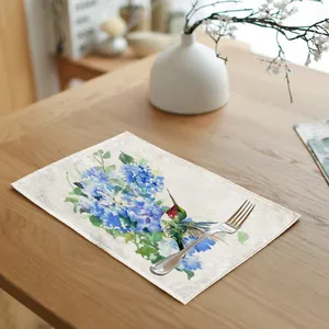 Close-up of linen placemat featuring watercolor hummingbird and blue floral design