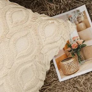 Detailopname van crème pluche kussensloop met getuft bladpatroon op een pluizig vloerkleed