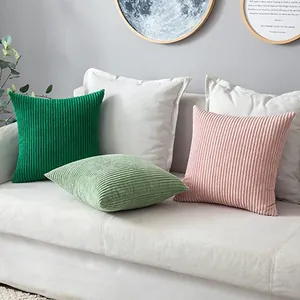 Detailweergave van gekleurde ribfluwelen kussenhoezen op een moderne witte bank.