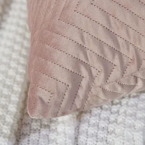 Close-up view of a pink quilted velvet throw pillow cover with a chevron pattern detail