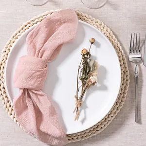 Macro detail of a soft pink crinkle cotton napkin knotted elegantly on a white dinner plate