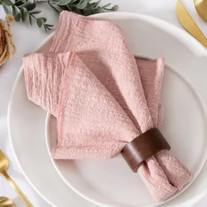 Macro view of a soft pink slub cotton napkin with a textured weave and wood ring