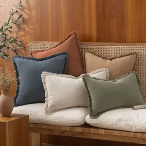 Earthy linen cushion covers with delicate fringe details on a stylish wooden bench