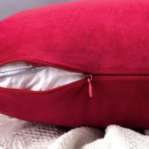 Detail view of a red velvet pillow cover featuring a hidden zipper and soft fabric texture