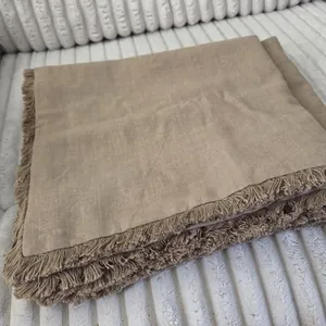 Close-up detail showing the texture of a natural linen pillowcase with fringe decoration