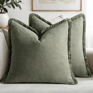 Detail of sage green natural linen pillowcases featuring elegant fringe edges on a modern sofa