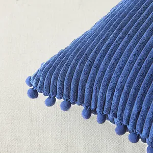 Funda de cojín de pana azul con ribete decorativo de pompones, detalle de textura