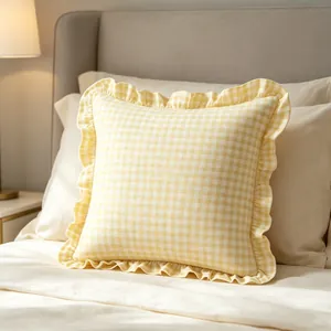 Close-up of yellow plaid throw pillowcase with ruffle edges on cozy bed.