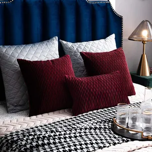 Luxury burgundy velvet pleated and silver quilted cushion covers on a modern bed.