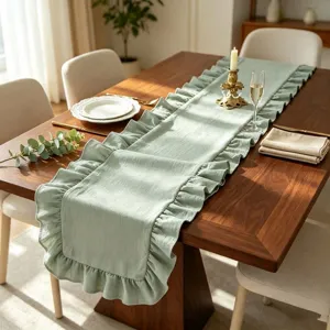Détail d'un chemin de table vert sauge avec bords à volants élégants sur bois.