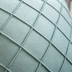 Close-up view of a teal velvet pillow cover featuring a textured diamond lattice pattern.