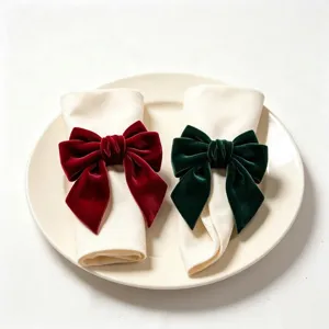 Detail shot of elegant burgundy and dark green velvet bow napkin rings on cream napkins