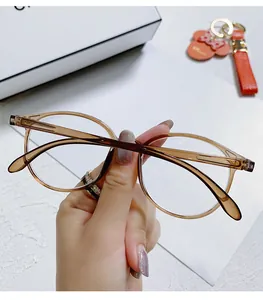 Vista detallada de gafas redondas ámbar con filtro de luz azul sostenidas por una mano