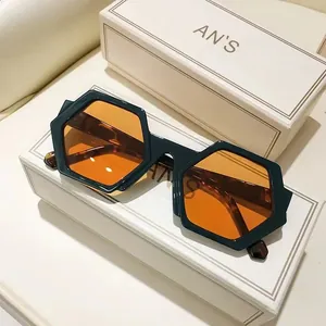 Stylish dark green hexagonal sunglasses with orange lenses, displayed on premium boxes.