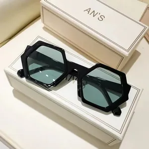 Modern black polygonal sunglasses with light green lenses on premium white gift boxes